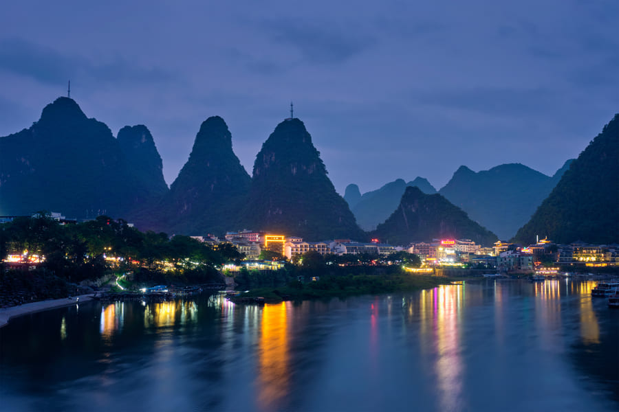 Toma panoramica de la hermosa ciudad de Yangsguo de noche con las monta;as de findo y el rio